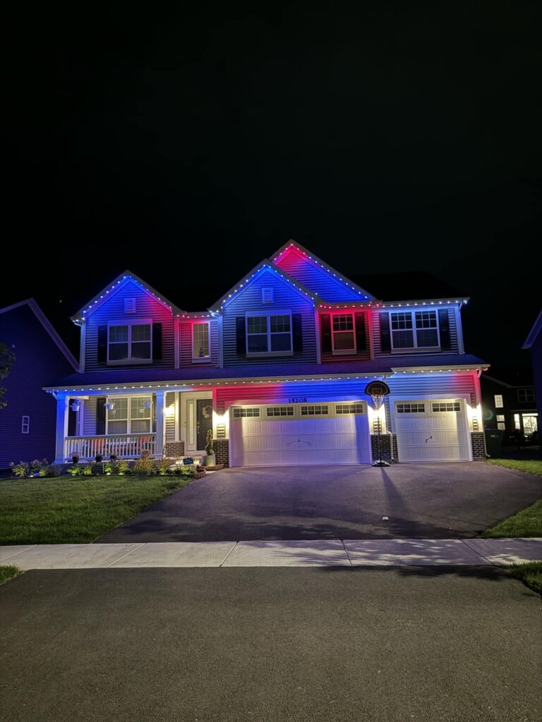 Red, white and blue permanent lights along the rooflines of a two-story home