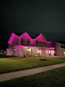Pink permanent lights along the rooflines of a two-story home
