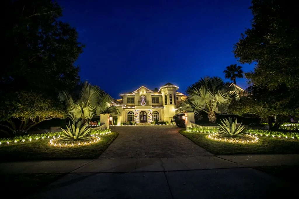 Luxury estate Christmas light installation in Central Florida with warm white roofline and tree lighting