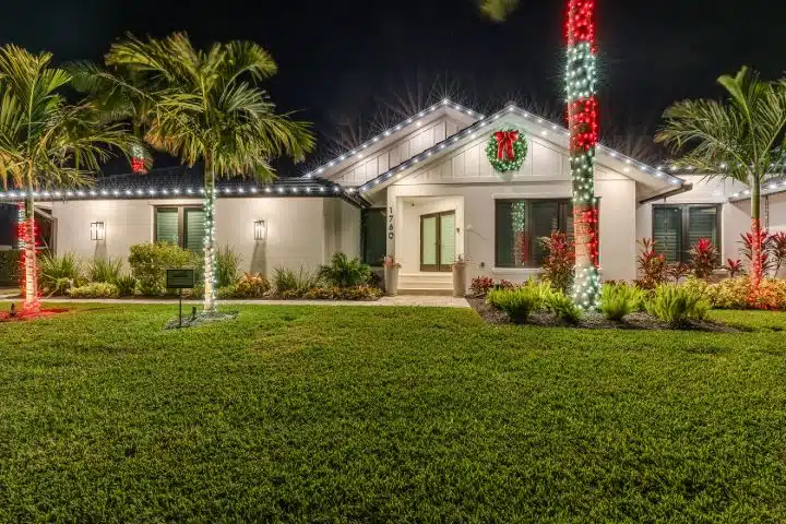 Christmas light installation Winter Park FL featuring warm white roofline and red green palm wraps