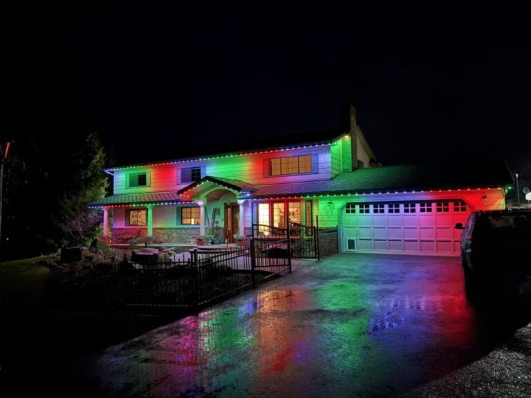 Multicolor permanent lights along a single-story roofline and garage at night