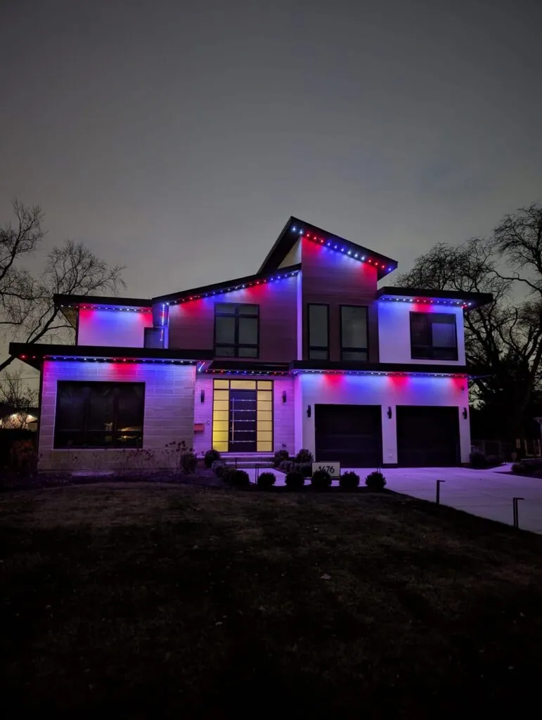 Red, blue and white permanent lights along a two-story roofline at night