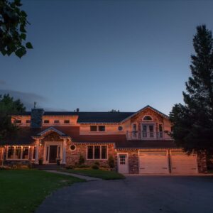 Warm white permanent lights along the rooflines of a two-story home at dusk