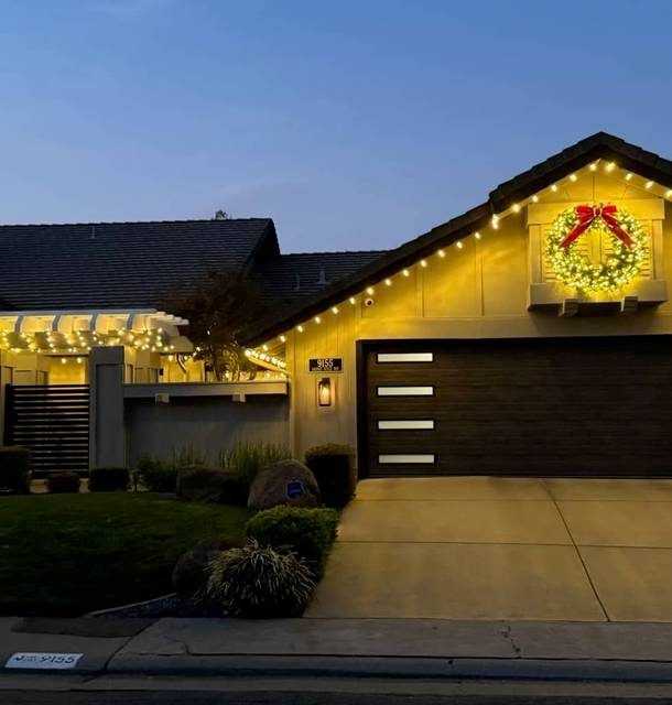 Warm white Christmas lights on a ranch roofline, with a lit wreath over the entry