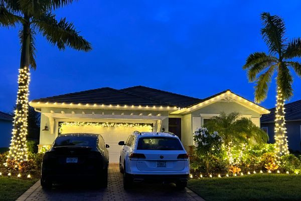 Villa with wrapped palm trees and lit garland over the garage